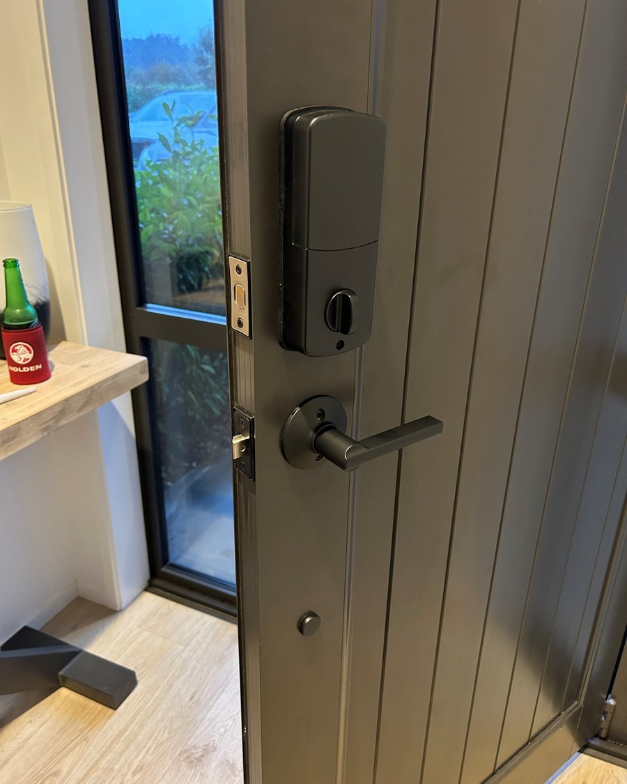 Smart deadbolt and lever fitted to a dark grooved timber entrance door, inside face