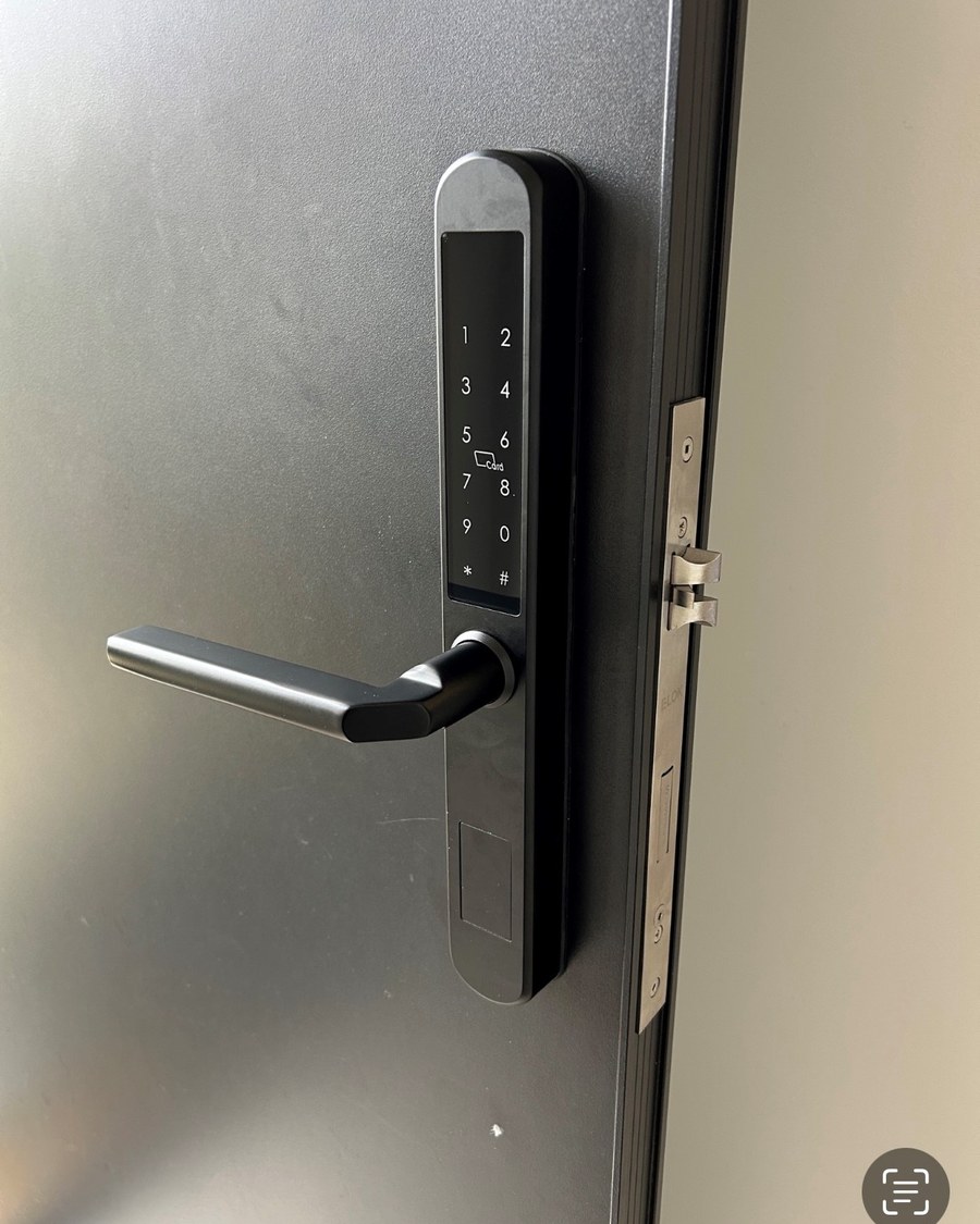 Dark slimline smart lock fitted to a grey aluminium door